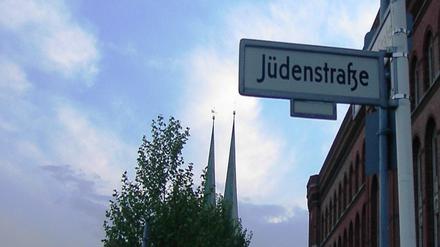 Straßenschild der Jüdenstraße am Roten Rathaus in Berlin-Mitte vor leicht bewölktem Himmel.