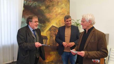 Mario Marcus (links), Schatzmeister der Gemeinde, übergibt ein Buch über die alte Synagoge an den Schenker des Gemäldes, Werner Brunner. Im Hintergrund: SPD-Chef Raed Saleh.