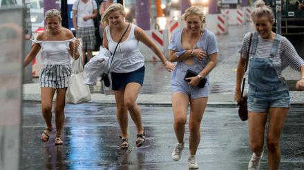 Touristinnen laufen in Berlin am Checkpoint Charlie durch den Regen. 