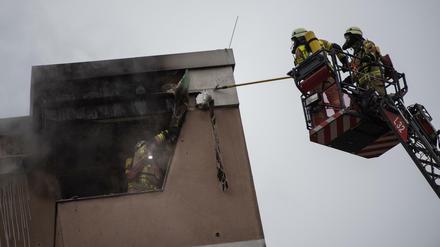 Feuerwehrmänner lösen die Verkleidung am Dach eines Hauses. Die Feuerwehr löschte einen Wohnungsbrand im Stadtteil Kreuzberg. 