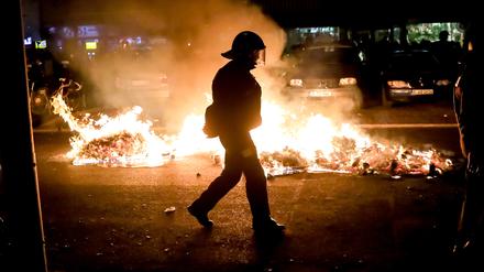 Ein Polizist geht an einem Feuer auf einer Straße am Rande der Demonstration linker und linksradikaler Gruppen unter dem Motto „Demonstration zum revolutionären 1. Mai“ vorbei.