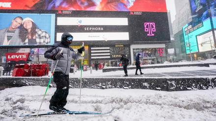 Eine Person fährt während eines Schneesturms auf Langlaufskiern über den Times Square.
