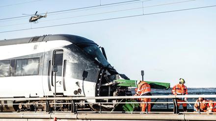 Rettungskräfte stehen an der Stelle eines Zugunfalls neben einem beschädigten Personenzug auf der Brücke über den Großen Belt bei Nyborg. 
