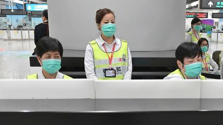 itarbeiter des Hongkonger Gesundheitswesens sollen Reisende am Bahnhof West Kowloon auf ihren Gesundheitszustand hin untersuchen und befragen. 