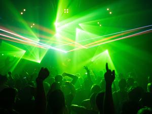 Eine Menschenmenge tanzt in einem Club vor einem DJ-Podest.