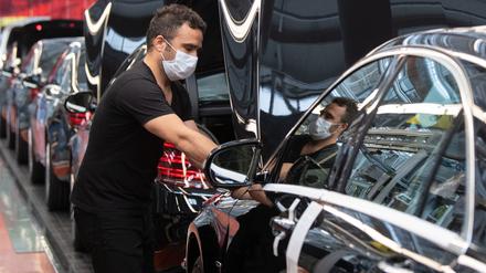 Ein Mitarbeiter der Daimler AG hat in der Produktion der S-Klasse einen Mundschutz an.