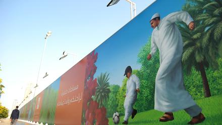 Ein Passant geht in Doha an einem Plakat vorbei, auf dem Einheimische Fussball spielen. 