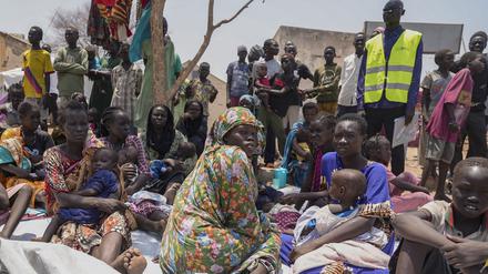 Südsudanesen, die aus dem Sudan geflohen sind, sitzen vor einer Ernährungsklinik in einem Transitzentrum. 