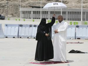 Eine Frau hält einen Schirm über einen Mann, der sein Gebet am letzten Tag der Hadsch in Mekka iN Saudi-Arabien verrichtet.