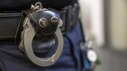 Eine Handschelle hängt am Gürtel eines Polizisten. (Symbolbild)