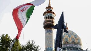 Iraner heben eine Flagge und die Attrappe einer Rakete während einer Feier nach dem iranischen Raketen- und Drohnenangriff auf Israel. 