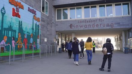 Menschen gehen am Landesamt für Einwanderung (LEA) am Friedrich-Krause-Ufer neben einem Wandbild entlang. Berlins Regierende Bürgermeisterin und die Innensenatorin wollen das LEA am selben Tag besuchen. +++ dpa-Bildfunk +++