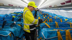Vor dem letzten Postflug befestigt ein Mitarbeiter der Wisag auf dem BER in einem Airbus A320-214 mit Stoffmanschetten abgedeckte Plastikboxen voller Briefe und anderer Post auf den Passagiersitzen. 