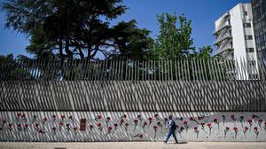 Ein Mann geht am 19. April 2024 in Lissabon an den mit roten Nelken geschmückten Wänden der Universität für Sozial- und Humanwissenschaften vorbei. 