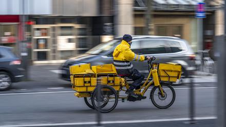 Eine Postbote ist auf einem Dreirad E-Bike unterwegs. 