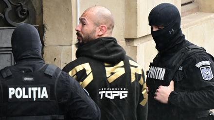 Der umstrittene Influencer Andrew Tate wird am 12. März 2024 von Polizeibeamten in das Gebäude des Berufungsgerichts in Bukarest (Rumänien) geführt.