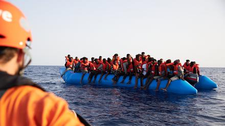 Ein Seenotretter schaut zu einem Flüchtlingsboot.