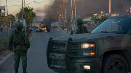 Ein mexikanischer Soldat neben einem brennenden Auto.