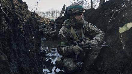 Ukrainische Soldaten hocken im Schlamm in einem Schützengraben an einer Frontlinie in der Nähe von Bachmut. 