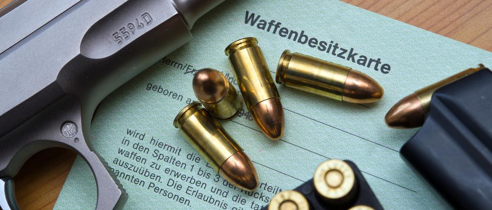 Eine Kaliber-9-mm-Pistole, Patronen und ein Magazin liegen auf einer Waffenbesitzkarte.