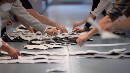 Wahlhelfer und Wahlhelferinnen zählen in einem Wahllokal Stimmzettel für die Bundestagswahl.