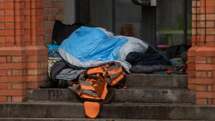 Ein Obdachloser liegt unter einer Decke in einem Eingang einer Kirche in Kreuzberg.