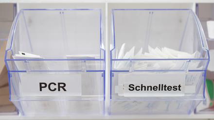 Abstrichstäbchen für PCR-Tests (links) und Corona-Schnelltests liegen in einem Corona-Testcenter in einem Spender.