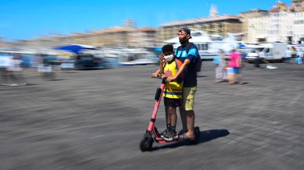 (FILES) In this file photo taken on August 26, 2020 youth wearing face masks ride a scooter in the old harbour of Marseille, southestern France. (Photo by Christophe SIMON / AFP)