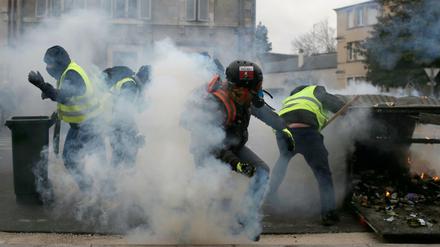 Teilnehmer einer Demonstration der "Gelbwesten" in Bourges gehen in Deckung, als die Polizei Tränengas einsetzt.