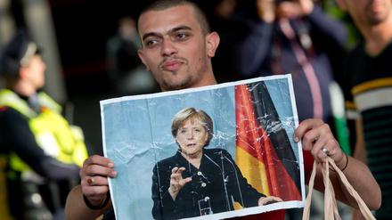 Ein Flüchtling hält am 05.09.2015 auf dem Hauptbahnhof in München ein Foto von Angela Merkel in den Händen. 