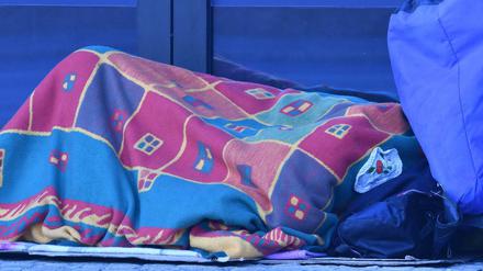 Ein Obdachloser schläft in Decken gehüllt in einem Hauseingang im Tiergarten. 