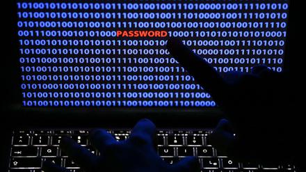 Ein Finger zeigt auf das Wort "Password", das zwischen Zeichen des Binärcode auf einem Computerbildschirm steht.