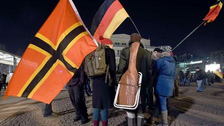 Legida-Teilnehmer ("Leipzig gegen die Islamisierung des Abendlandes") ziehen mit einer Flagge, die im Jahr 1944 von Josef Wirmer als Nationalflagge vorgeschlagen wurde, und einer Deutschlandfahne durch Leipzig. 
