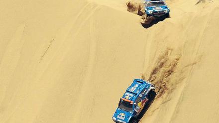 Dünenstürmer. Nasser Al-Attiyah aus Katar (unten) führt die Rallye Dakar knapp vor seinem spanischen VW-Teamkollegen Carlos Sainz an, Volkswagen wird den Wettbewerb wohl zum dritten Mal in Folge gewinnen. Foto: AFP