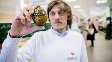 Sirplus-Gründer Raphael Fellmer hält eine fleckige Avocado.