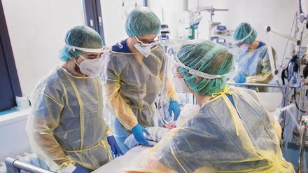 Pfleger und Pflegerinnen tragen Schutzklamotten auf einer Intensivstation für Corona-Patienten. 